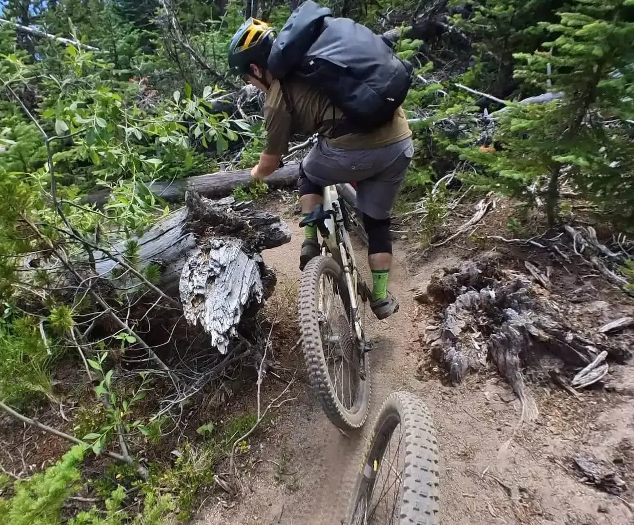 Rider con lo zaino in un tratto tecnico e roccioso della discesa nei Chilcotins