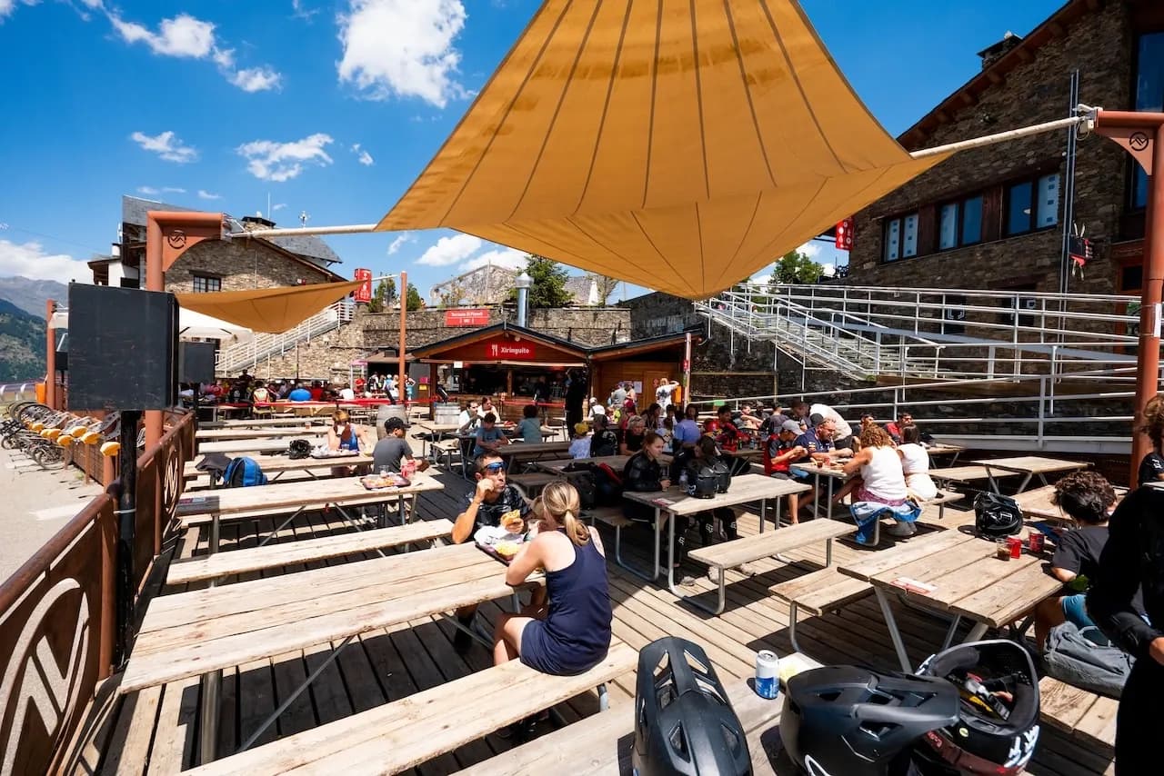 Rider beim Essen an den Holztischen der sonnigen Terrasse des Bike Parks