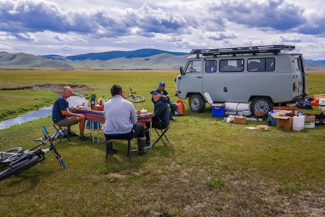 Mittagessen der Gruppe neben dem Begleitfahrzeug in der Steppe