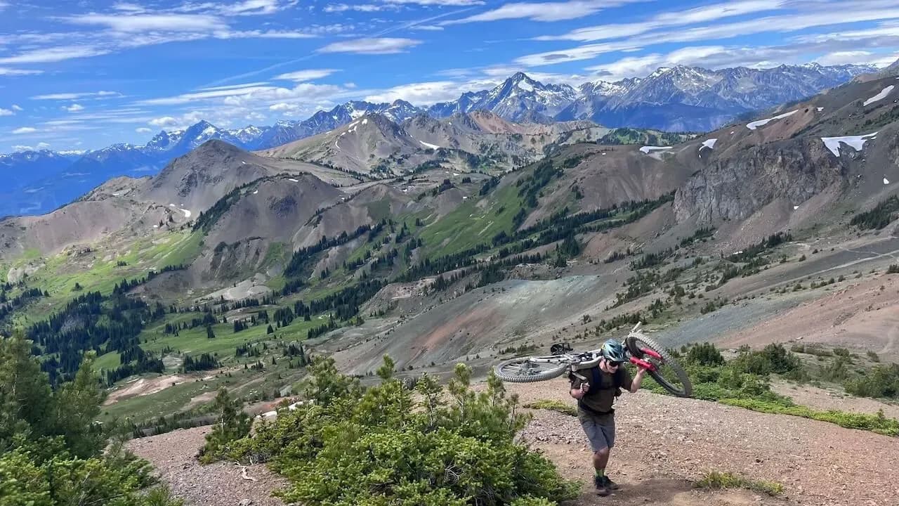 Rider trägt sein Bike auf den Schultern beim letzten Hike-a-Bike hinauf zum Grat in den South Chilcotins