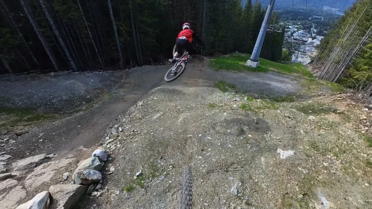 Rider auf einem Downhill-Bike fährt unter einem Sessellift im Whistler Bike Park in einen Anlieger